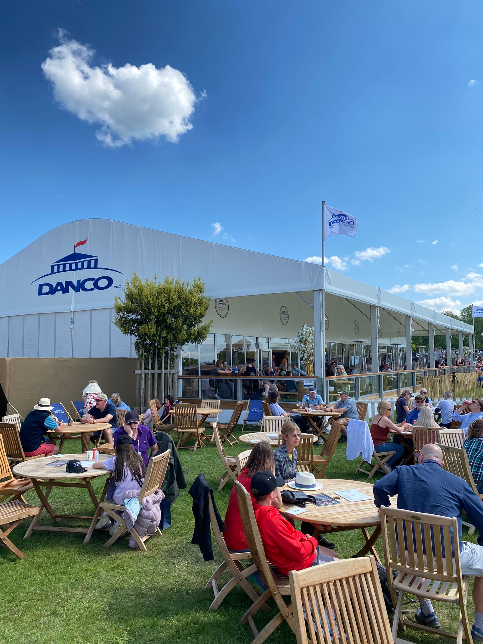 People enjoying drinks and food outside the Danco Hospitality marquee at Badminton Horse Trials