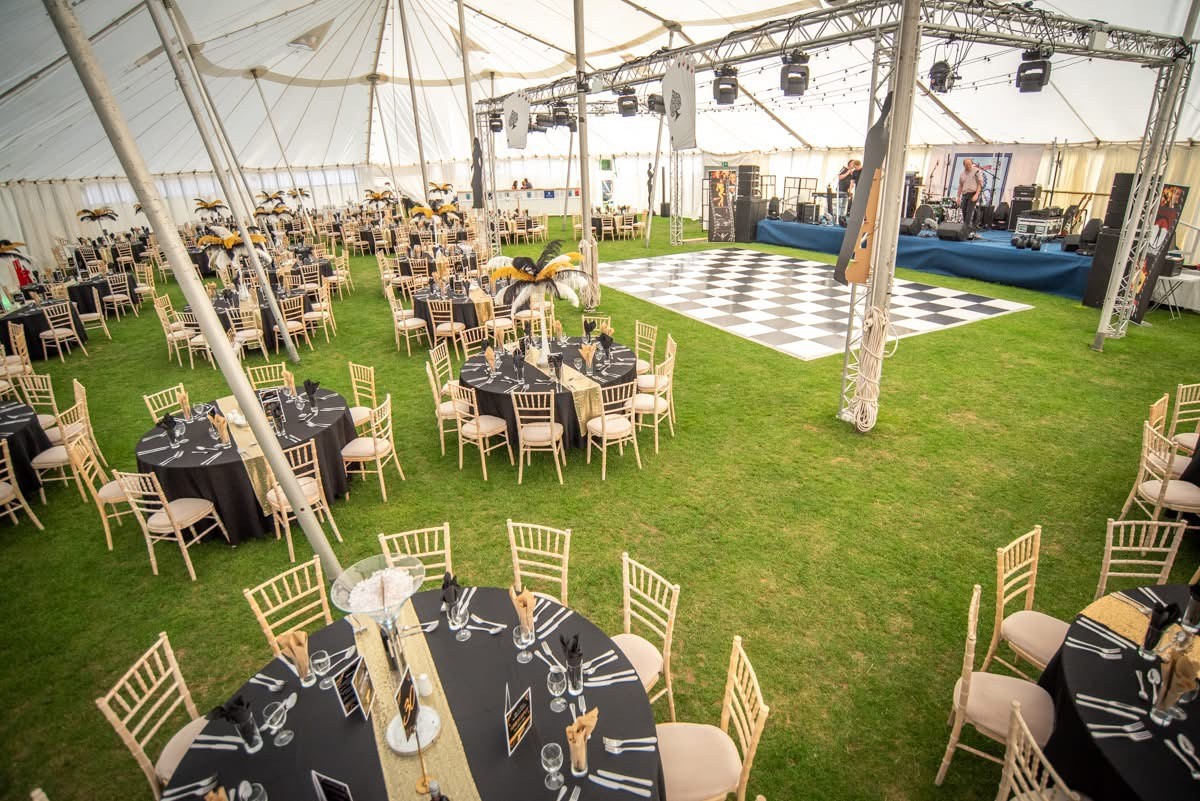 The inside of a tradional marquee with decorated tables, chairs and dance floor for a school leavers prom. 