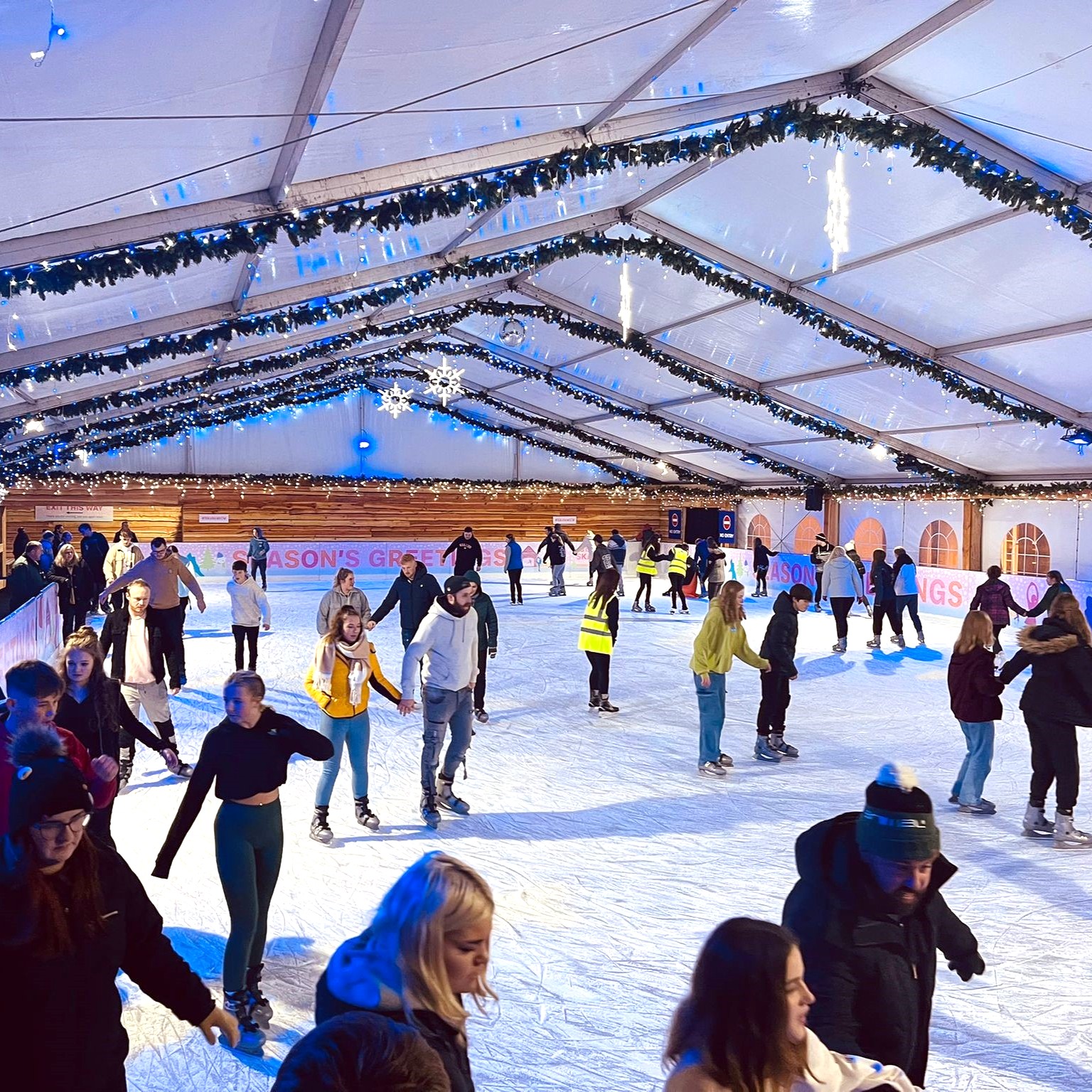 Clarks Village Ice Rink in Somerset. Undercover inside a clear roofed marquee, skaters enjoy the skating on the ice whatever the weather. 