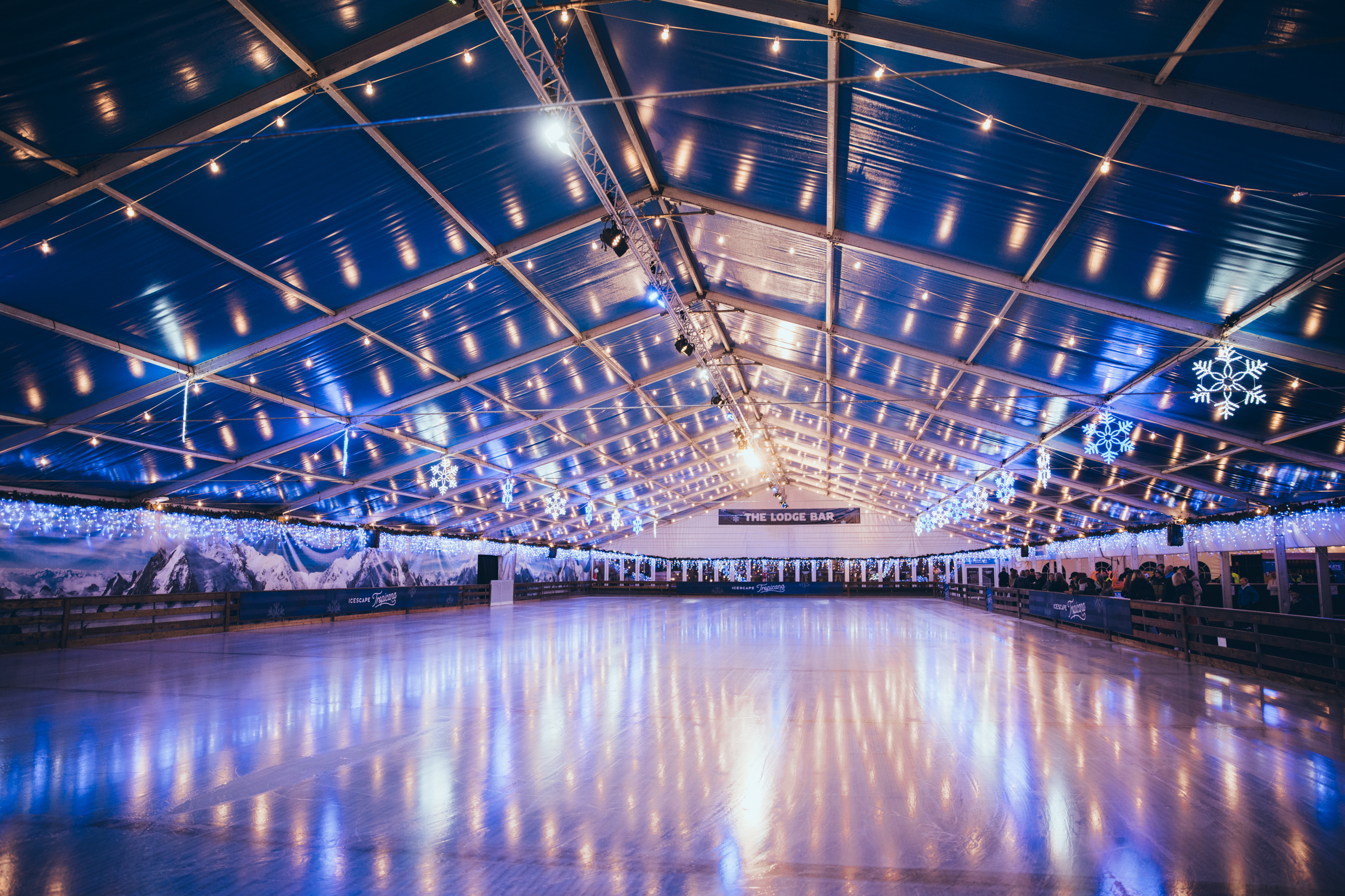 A large winter real ice rink glittering under lights inside a huge marquee structure. 